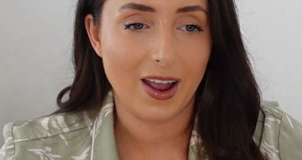 Hazel Maria Wood is seen wearing a sage green and white pyjama top. She sits in front of an off-white wall. Hazel has her black hair loose and pushed to one side.